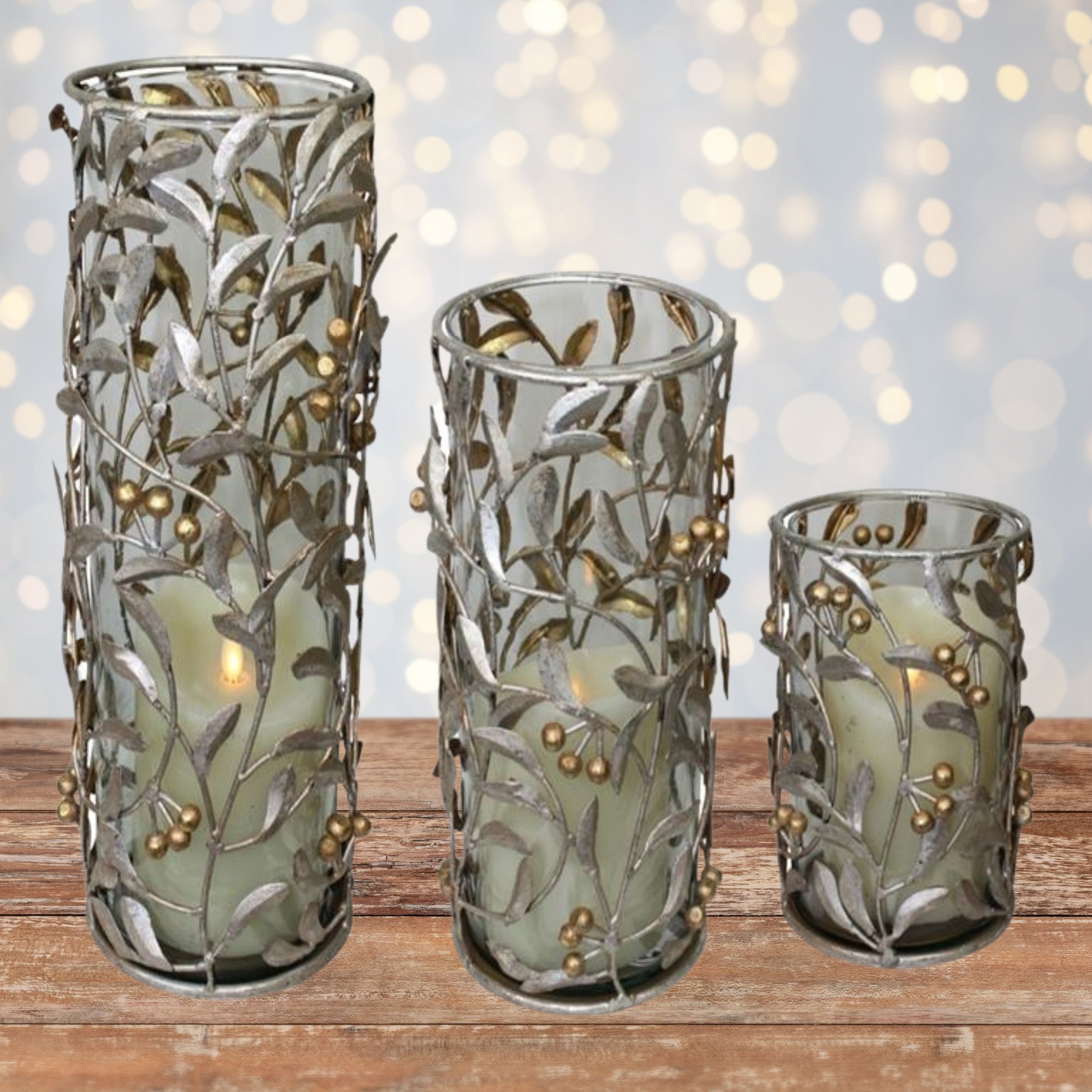 Set of three large decorative glass hurricane candle holders with leaf and berry design on a wooden surface makes an elegant Christmas decoration | oak7west.com