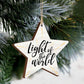 Star-shaped ornament with 'Light of the World' text hanging on a Christmas tree. | oak7west.com