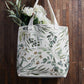Green leaf design on tote bag with flowers on a dark wood background | Canvas Tote Bag with Inside Zippered Pocket - Loved | oak7west.com