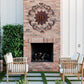 Outdoor patio with brick fireplace, wooden chairs, and decorative wall art | Monogrammed Iron Wall Grille - Personalized Wall Decor (33"W) | oak7west.com