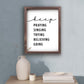 Framed motivational poster with inspirational quote on a wall above a table with decor items | keep PRAYING SINGING TRYING BELIEVING GOING - Inspirational Christian Wall Decor | oak7west.com
