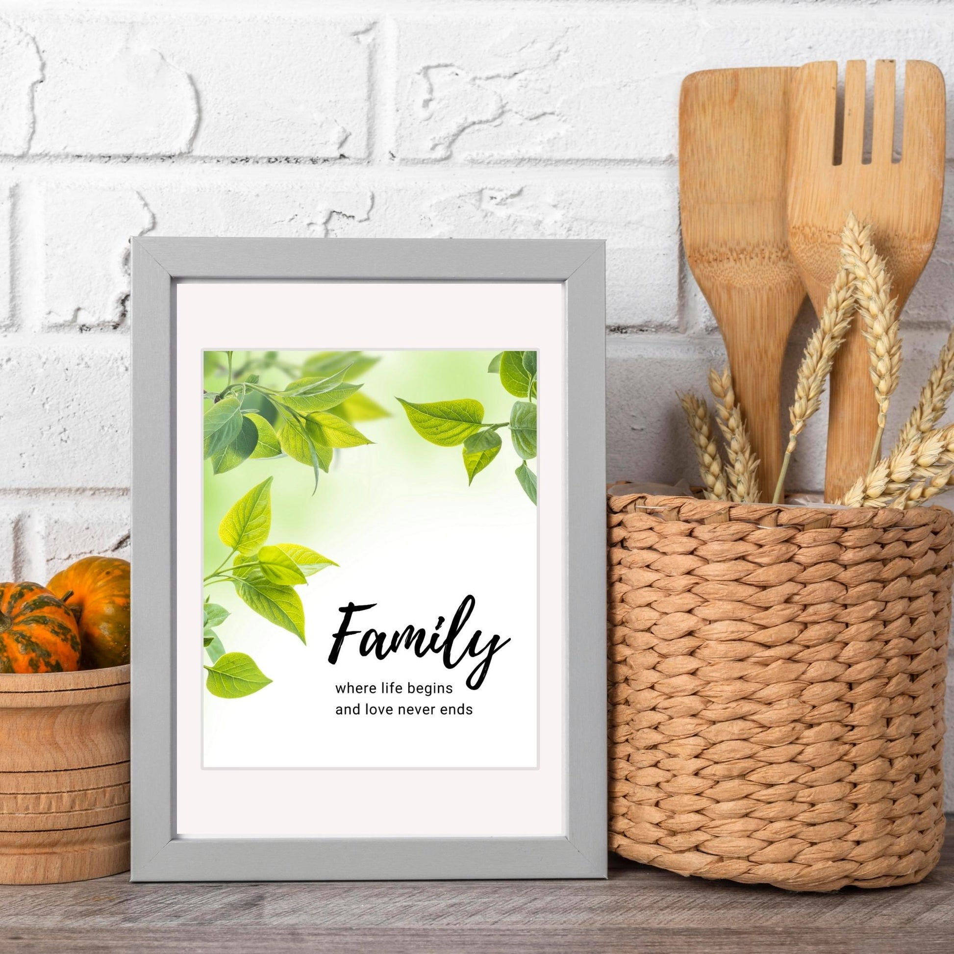 Inspirational Word Art - Family, where life begins and love never ends - Green Leaves Wall Decor (8x10 print) | shown in light grey frame on kitchen counter with white brick backsplash | oak7west.com
