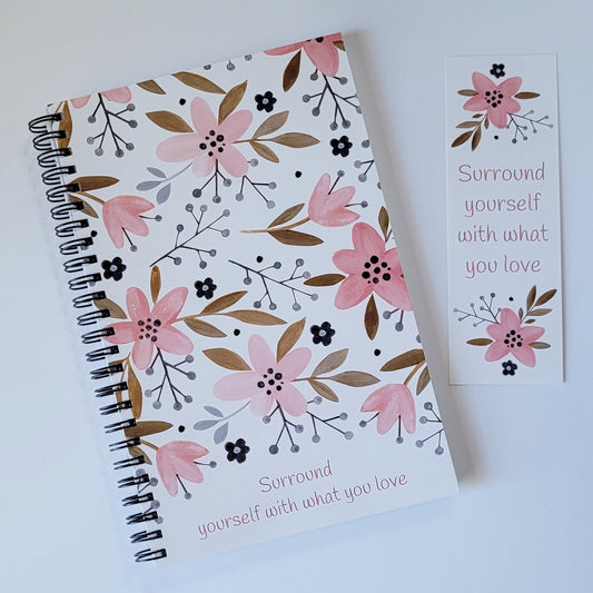 Our exclusive notebook designed in-house has a cute floral print in pinks, tans, and navy blue. The cover reads "Surround yourself with what you love" in a fun pink font. The floral design also decorates the back cover with the words "be a blessing... today, tomorrow, always". Shown with matching bookmark FREE with purchase of notebook. | oak7west.com